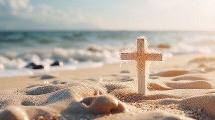 Small wooden Christian cross in sand on the beach with sea in background and copy space