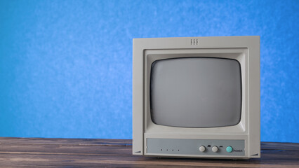 A gray antique TV on a wooden table on a blue background.
