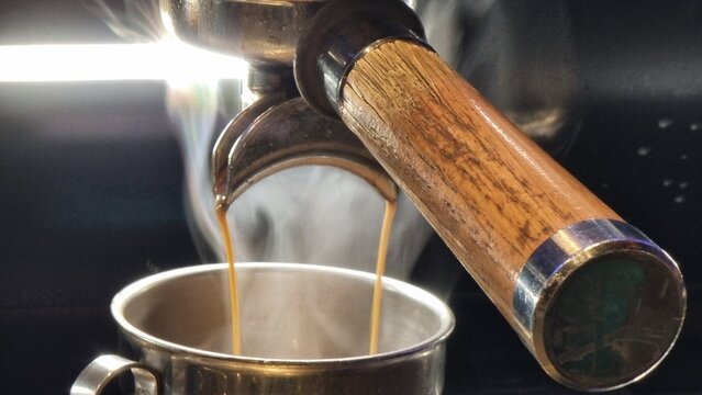 coffee making machine in coffee shop pouring hot coffee with steam