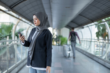 Fototapeta premium Asian beautiful muslim woman wear hijab talking with mobile phone. Islamic female walking and using telephone warking city street.