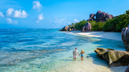 Anse Source d'Argent beach La Digue Island Seychelles, a couple of men and woman walking at the beach at a luxury vacation. a couple swimming in the turqouse colored ocean of La Digue Seychelles - obrazy, fototapety, plakaty