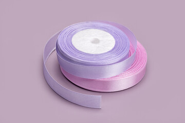 Two rolls of satin ribbon for gift wrapping, lilac background. Studio shot.