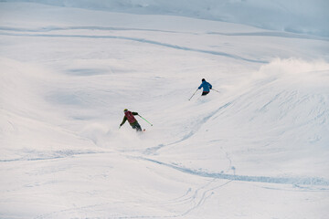 Two skiers on skis go down the snowy slope together