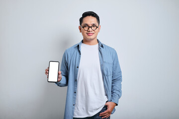 Portrait of young handsome handsome man wearing denim and glasses showing his blank screen phone...