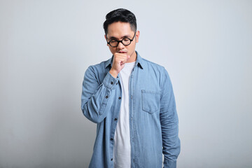 Portrait of young asian man wearing denim and glasses coughing with sore throat