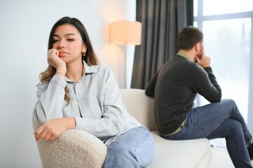 Man and woman feeling stressed and angry at each other, frustrated couple sitting back to back,...