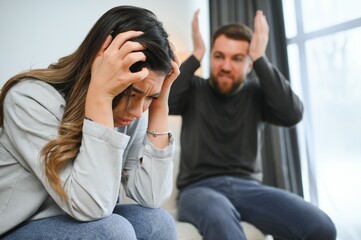 Emotional man gesturing and shouting at his wife, young couple having quarrel at home. Domestic abuse concept