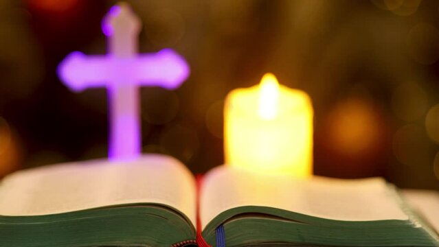 open bible of the gospel against a blurry background of a cross and candles