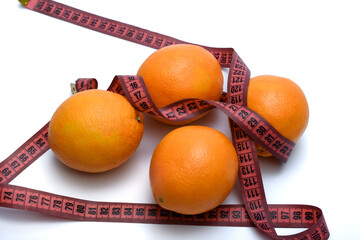 Pomarańcze leżą owinięte centymetrem na białym tle - obrazy, fototapety, plakaty