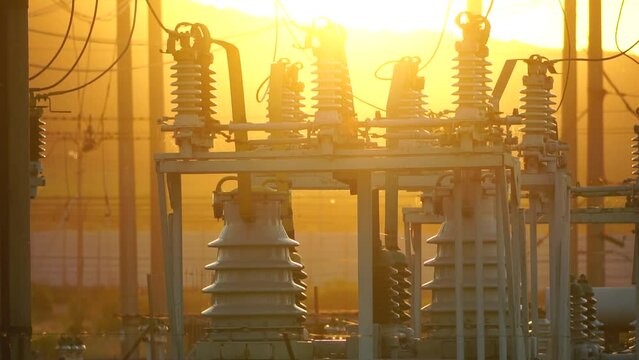 High voltage electric transformer station and distribution network at sunset. Power transmission lines on supports with ceramic insulators and transformers at large electrical distribution substation