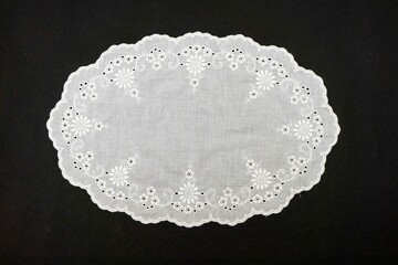 Vintage handmade white knitted napkin isolated on a black background.