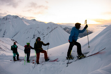 Close-up of four skiers climbing another slope, admiring the beautiful mountain landscape