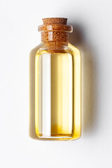 Top-down view of a round glass bottle containing pale yellow color essential oil for cosmetics and natural medicine.