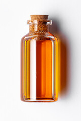 Top-down view of a round glass bottle containing dark orange color essential oil for cosmetics and natural medicine.