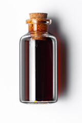 Top-down view of a round glass bottle containing dark amber color essential oil for cosmetics and natural medicine.