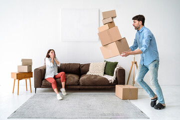 Shocked young adult man dropping cardboard boxes, looking how package fall