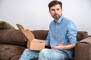 Confused young man getting poor quality goods from online shop