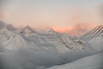 Beautiful snowy slopes against the background of the crimson sun - obrazy, fototapety, plakaty