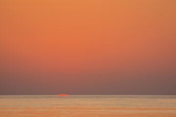 orange red sky one second after sunrise with sun at the horizon from the red sea