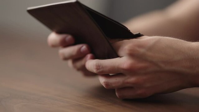 Slow motion closeup man counting money in brown leather wallet