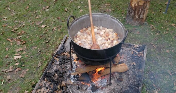 Preparation of delicious unhealthy fried pork greaves in a cauldron on the open fire. Delicious fried pork greaves in the pan traditional Romanian Christmas dish. Crispy deep fried