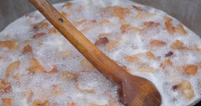 Preparation of delicious unhealthy fried pork greaves in a cauldron on the open fire. Delicious fried pork greaves in the pan traditional Romanian Christmas dish. Crispy deep fried