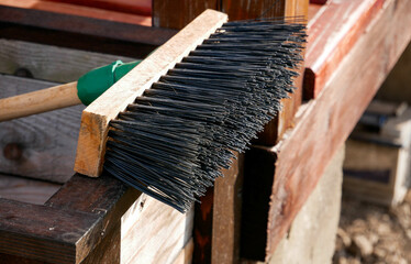Plastic broom with wooden handle close up shot under harsh sunlight.