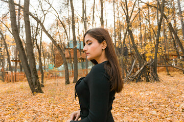 Close-up portrait of diversity young beautiful confident Indian Asian woman in black dress in fall outdoor copy space mockup. Happy and natural smiling female. Generation z and gen z youth concept