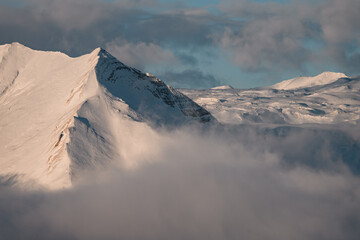 Photo beautifully combines a rocky mountain slope, a snowy plain and a foggy strip