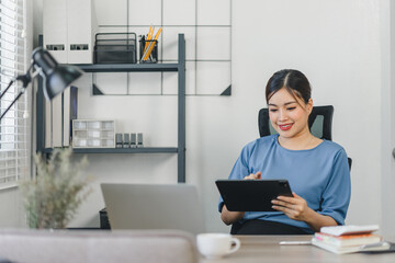 Beautiful asian small business owner using tablet while working at home.