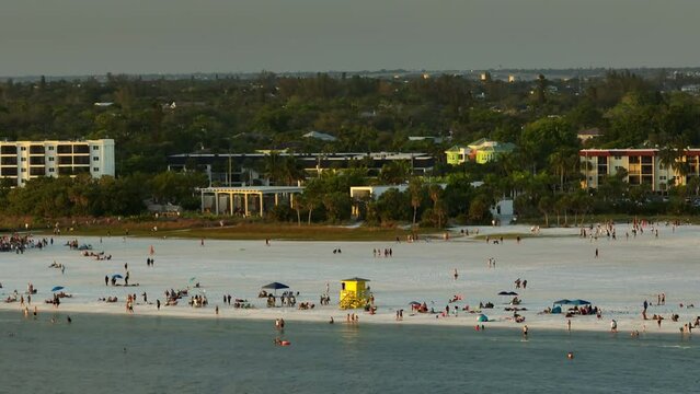 Famous Siesta Key beach with soft white sand in Sarasota, USA. Many people enjoying vacation time bathing in warm gulf water and tanning under hot Florida sun at sunset