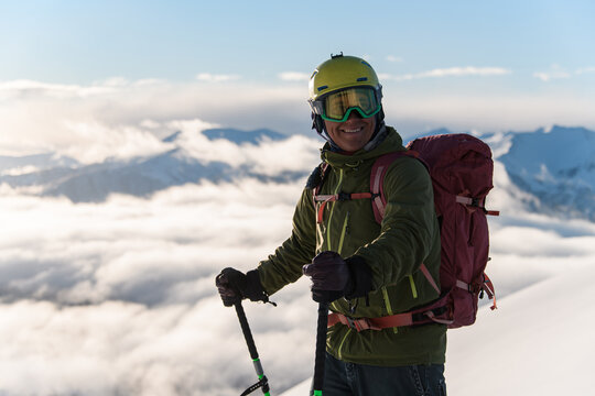 Close-up photo of a happy freerider standing on skis on top of the highest mountain