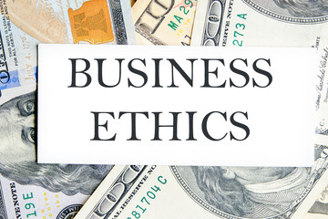 BUSINESS ETHICS text, a word written on a white business card against a background of money