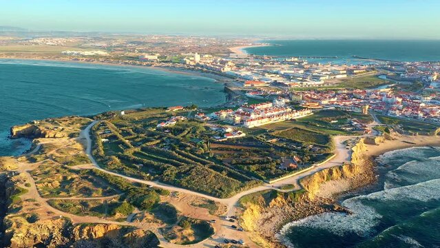 Pull back revealing drone shot Peniche, town, cliffs and sunset