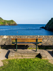 Bench on the beach at Readymoney Cove with a view across the river Fowey towards Polruan, Cornwall, England, UK