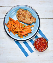 Healthy fitness food, sweet potato fries, chicken steak and hot tomato sauce with chili. Vertical photo