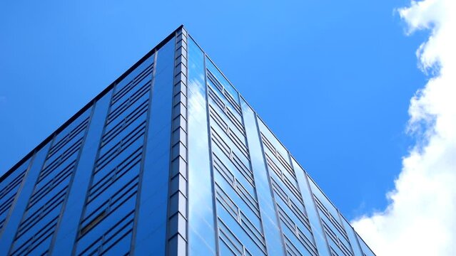 Tall big office building with white clouds, blue clean sky background. Time lapse, tower, highrise, facade, high, estate, center, glass, glazed, windows, place, city, wall, cloud, hd. ProRes 422 HQ.