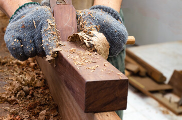 Carpenter's hands planing a plank of wood with a hand plane
