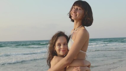mother hugs her son on the beach. happy family on vacation. mother and son are having fun on the beach near the sea.