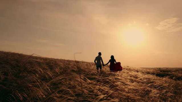 Silhouette of a man and woman at sunset, in slow motion. Love story, happy family. Romantic date and love in nature of loving happy couple