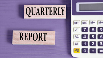 QUARTERLY REPORT - words on wooden blocks with a calculator in the background