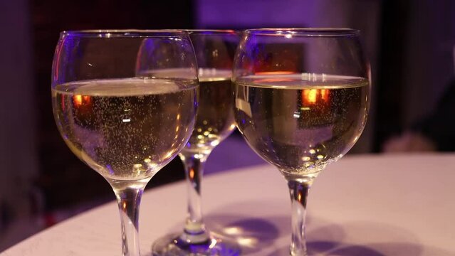 Three glasses of champagne standing near fireplace. Closeup view of wine glasses with bubbles
