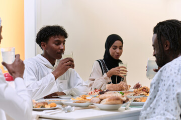 Fototapeta na wymiar A traditional and diverse Muslim family comes together to share a delicious iftar meal during the sacred month of Ramadan, embodying the essence of familial joy, cultural richness, and spiritual unity
