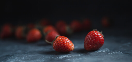 Close-up of bright red ripe strawberries on a black background.
