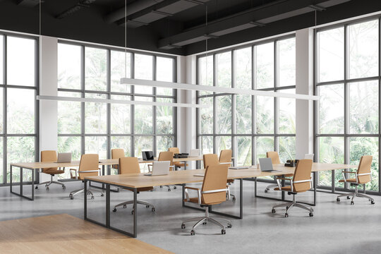 Light workplace interior with shared desk and laptop, panoramic window