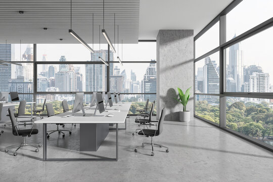 Coworking interior with desk and pc monitors in row, panoramic window