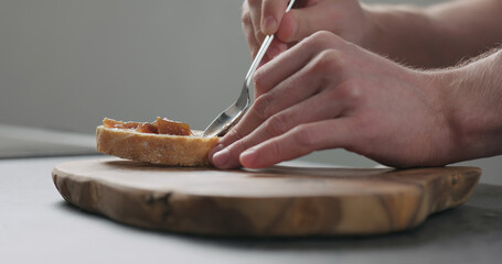 Obraz na płótnie Canvas man spread fig marmalade on ciabatta bread