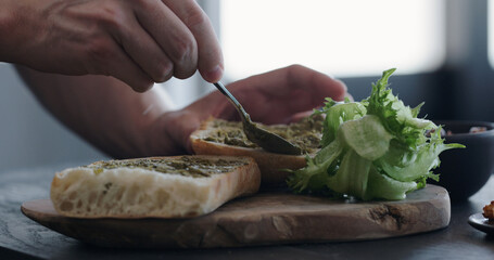 man making ciabatta sandwich with shrimps, olives and pesto