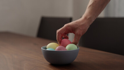 Man hand take easter eggs from a bowl on walnut table