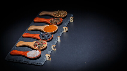 All types of spices on a black background, different spices in spoons on a black background, beautiful spices in spoons